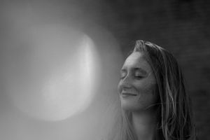 Artistic black and white portrait with dramatic lighting and peaceful expression.