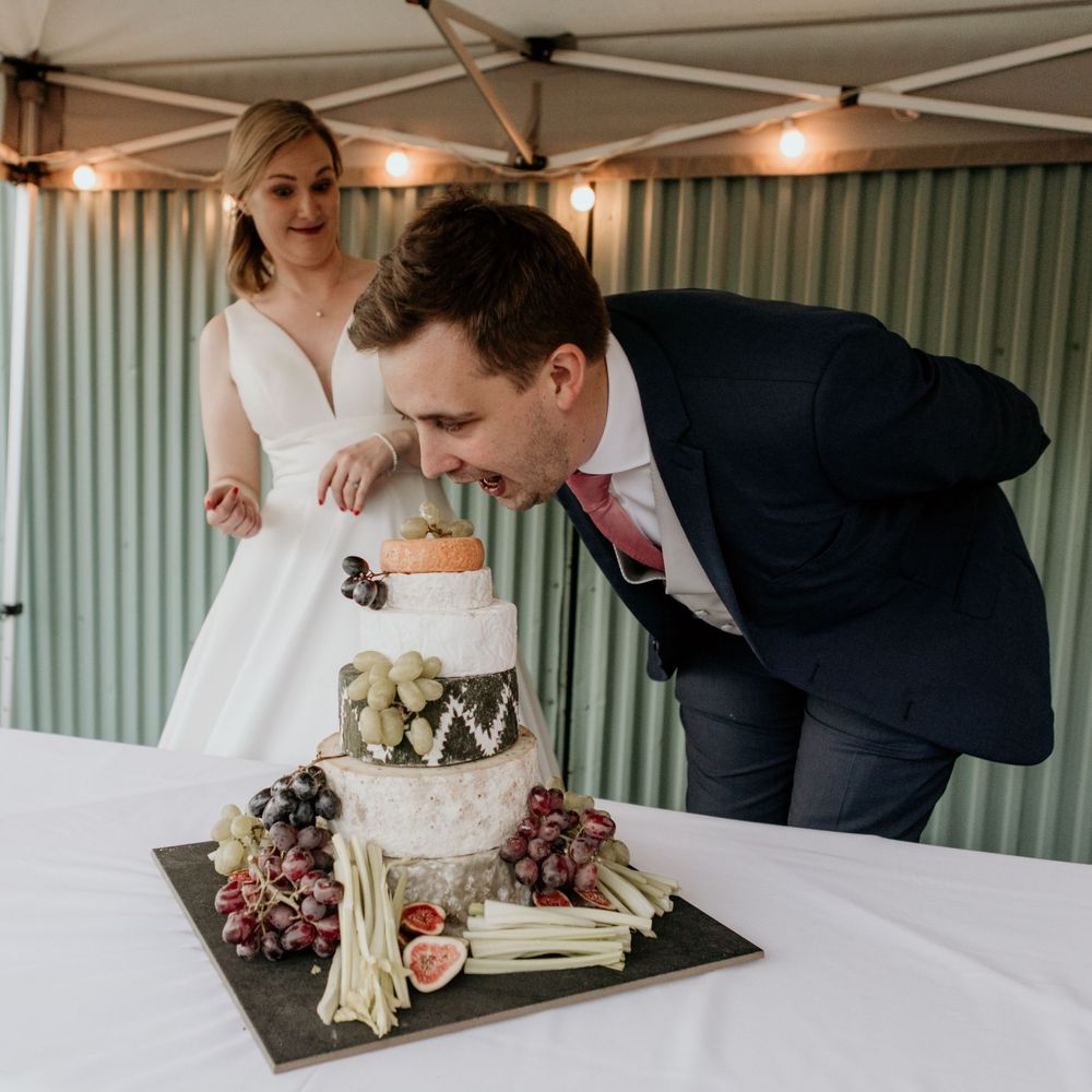 Couple tasting their decorated wedding cake with fresh fruits and flowers.