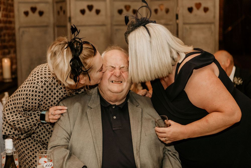 Candid moment of wedding guests sharing laughs at reception party.