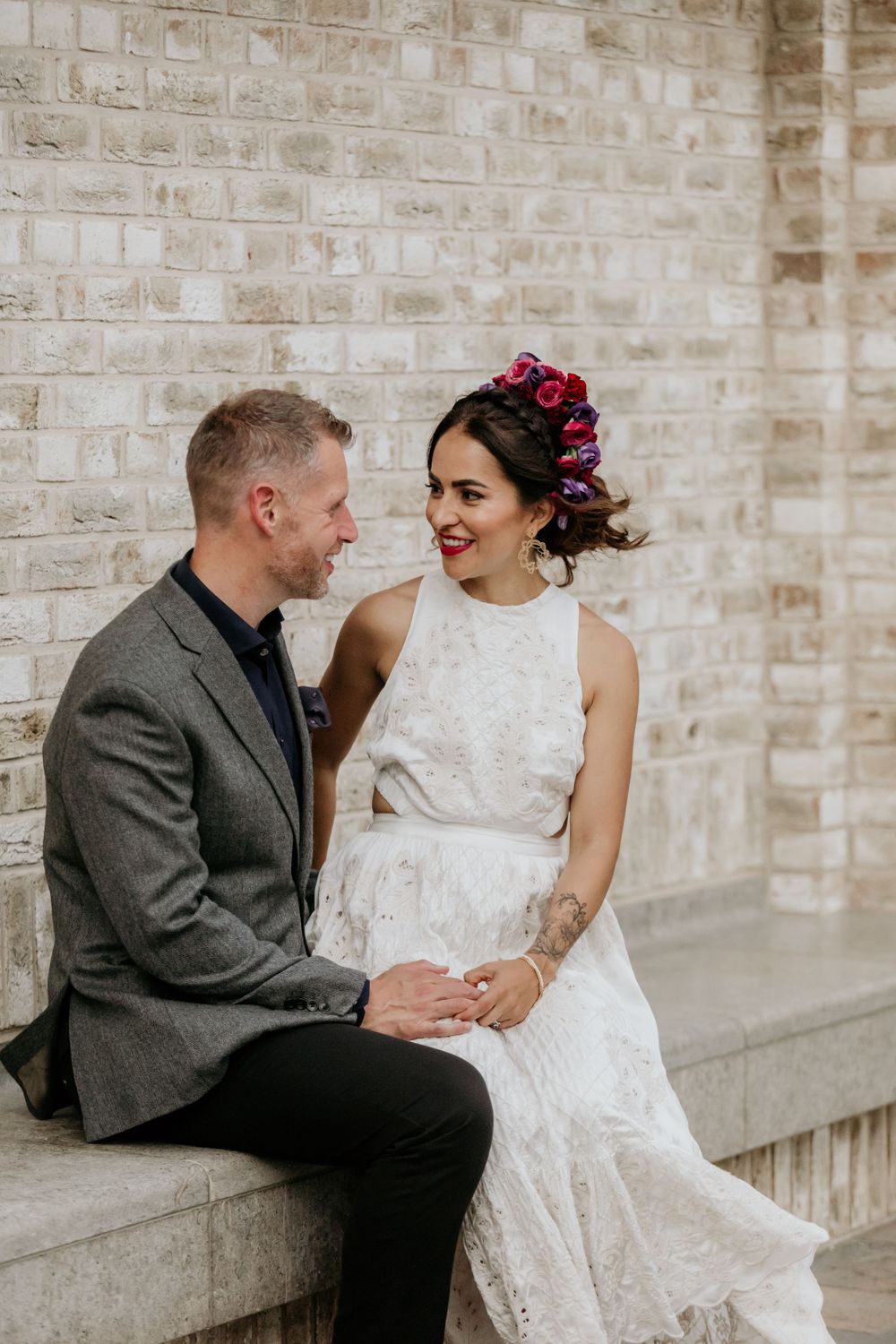 A couple sits together on a stone ledge during their wedding portraits.