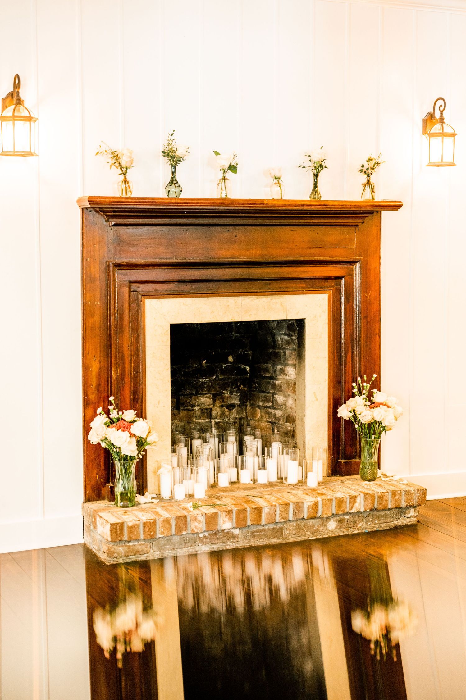 Elegant fireplace mantels decorated with candles and floral arrangements for wedding reception.