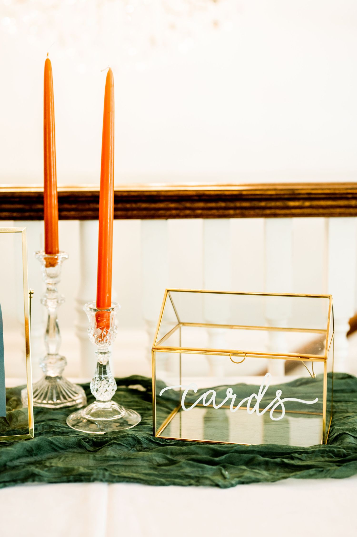 Orange candles and acrylic signs arranged on emerald velvet table runner for wedding decor.