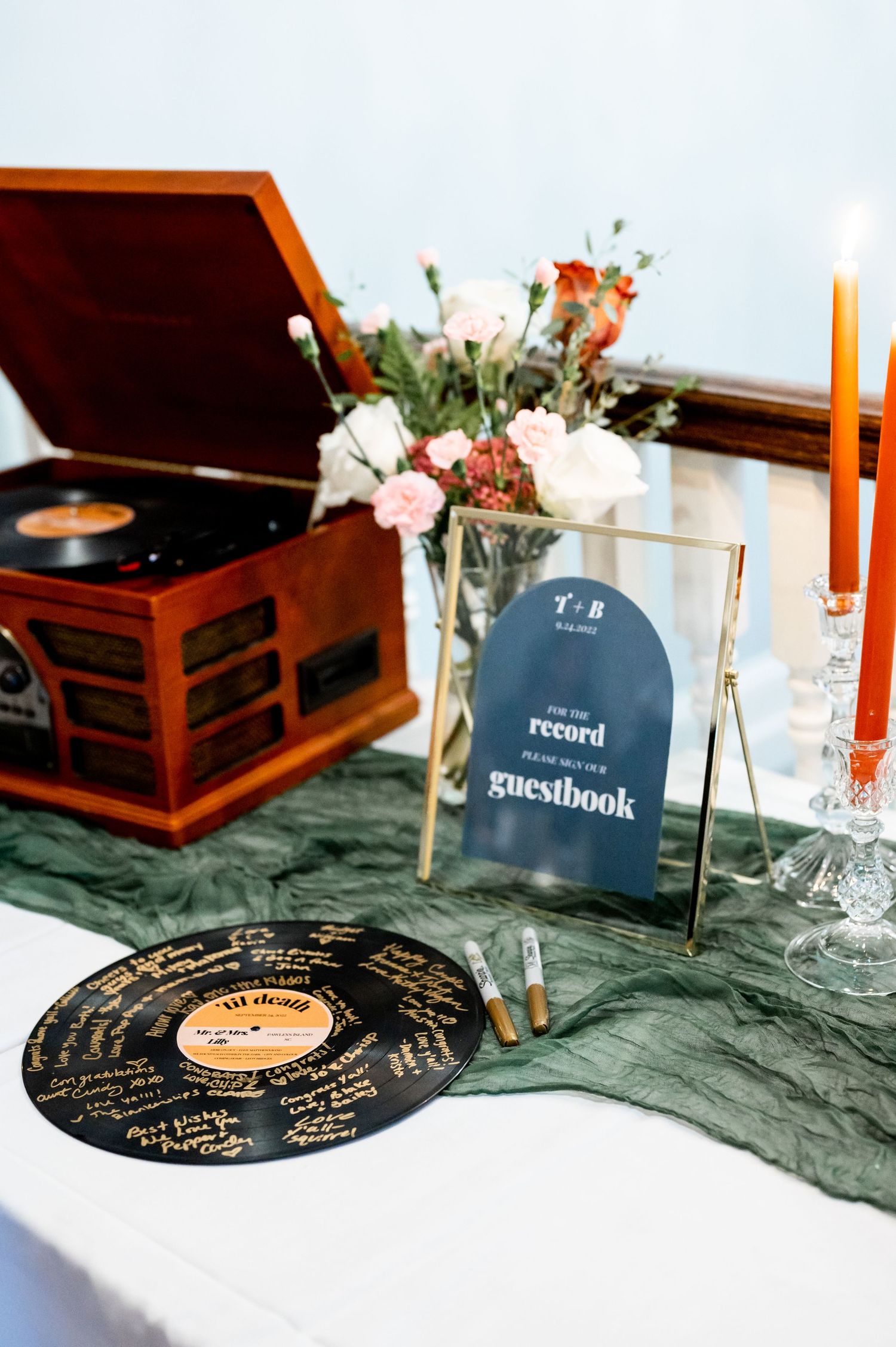 Vintage record player and vinyl records arranged as wedding decor with floral accents.