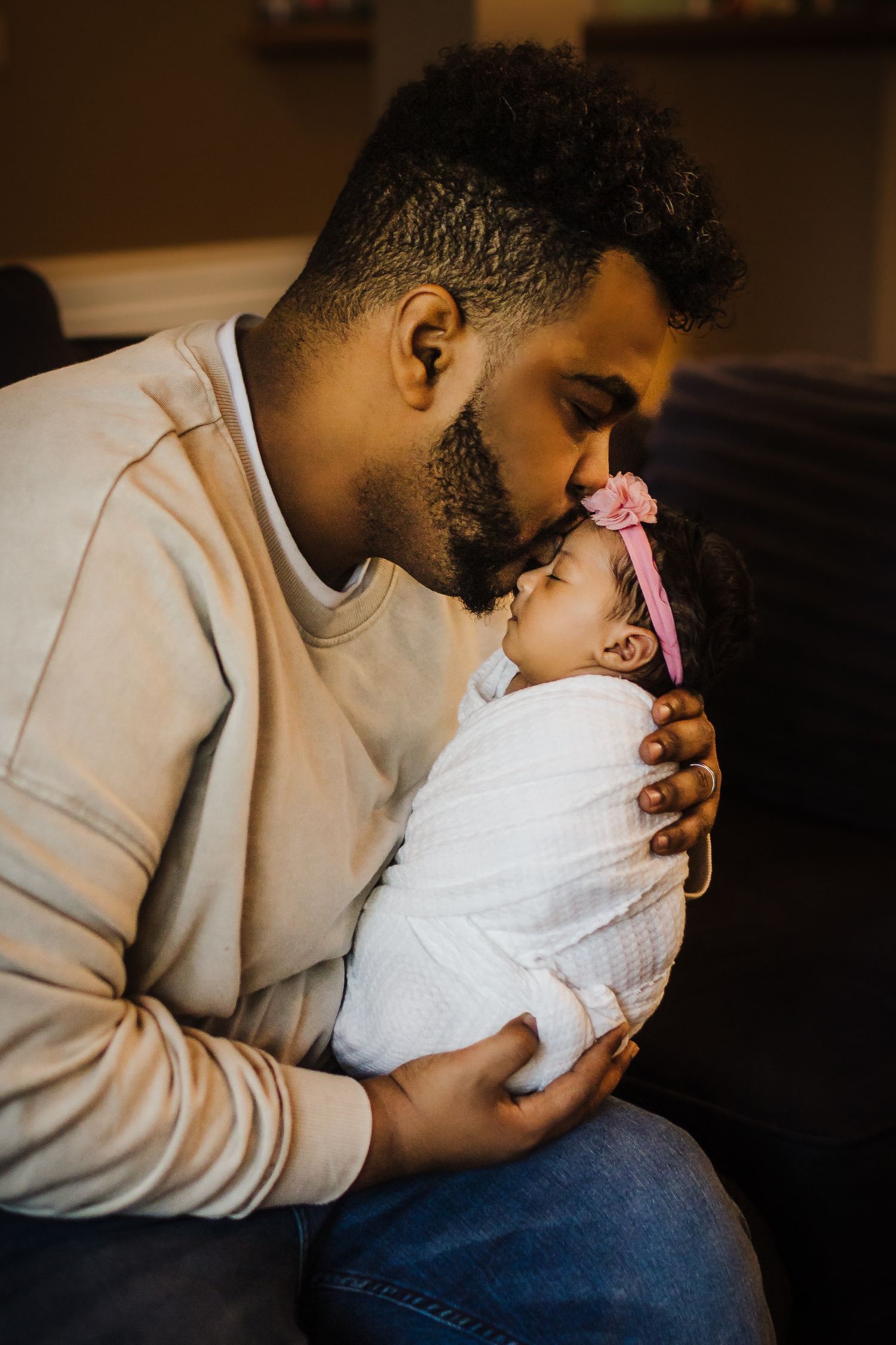 Tender moment between parent and newborn wrapped in white.