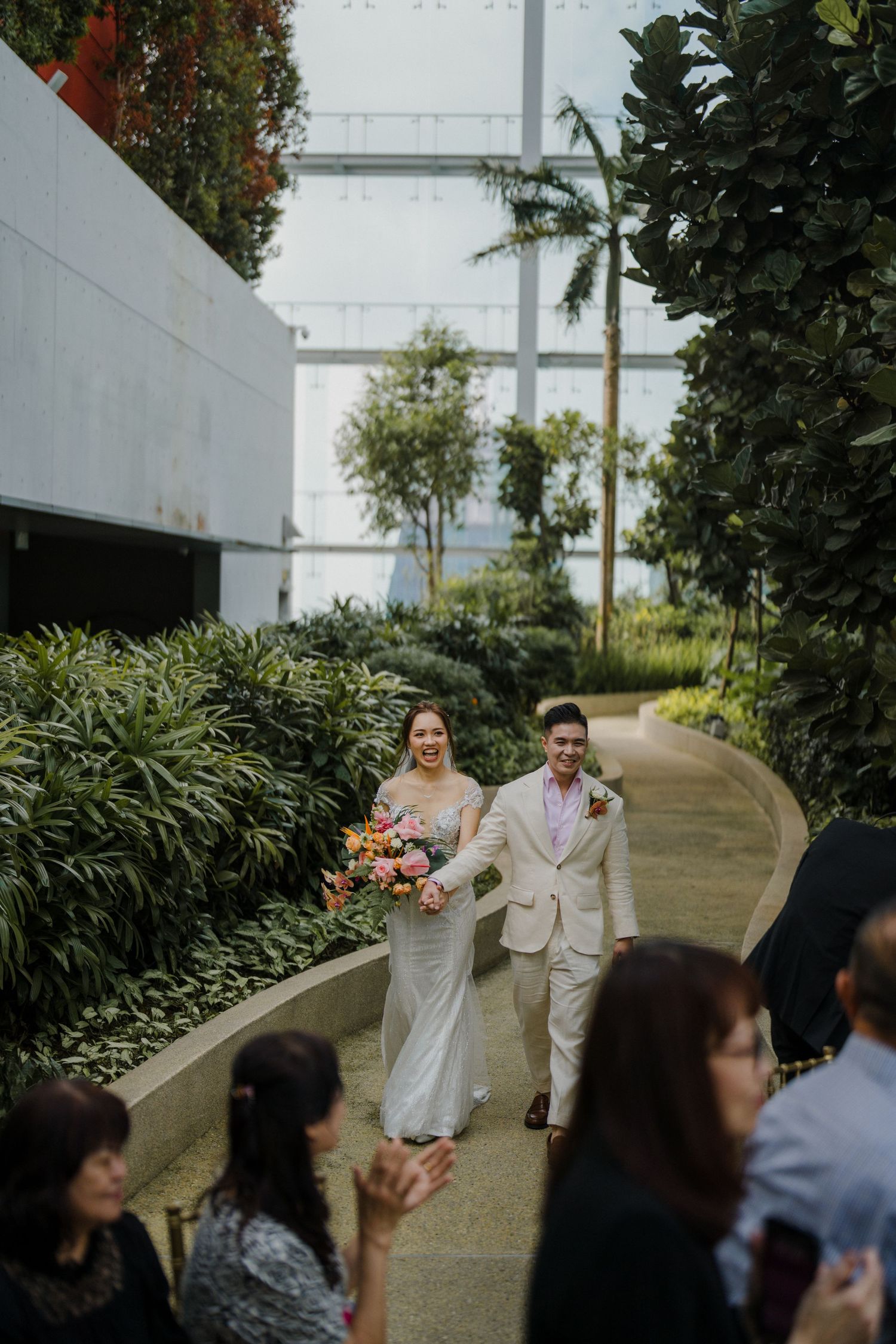 Wedding couple making their entrance along a landscaped garden walkway.