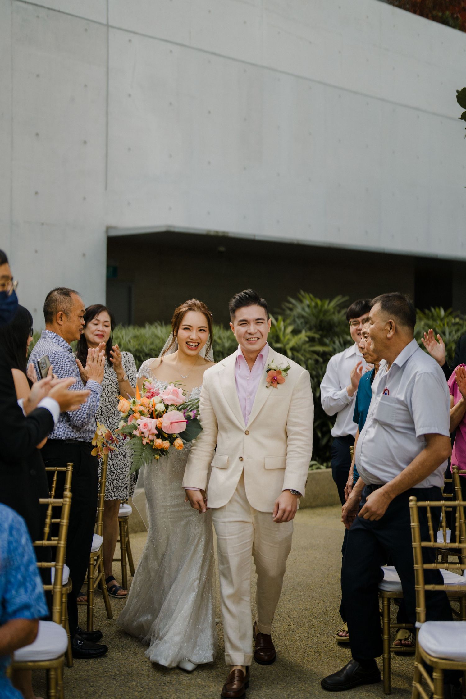 Wedding celebration in a modern garden venue with guests and tropical decor.