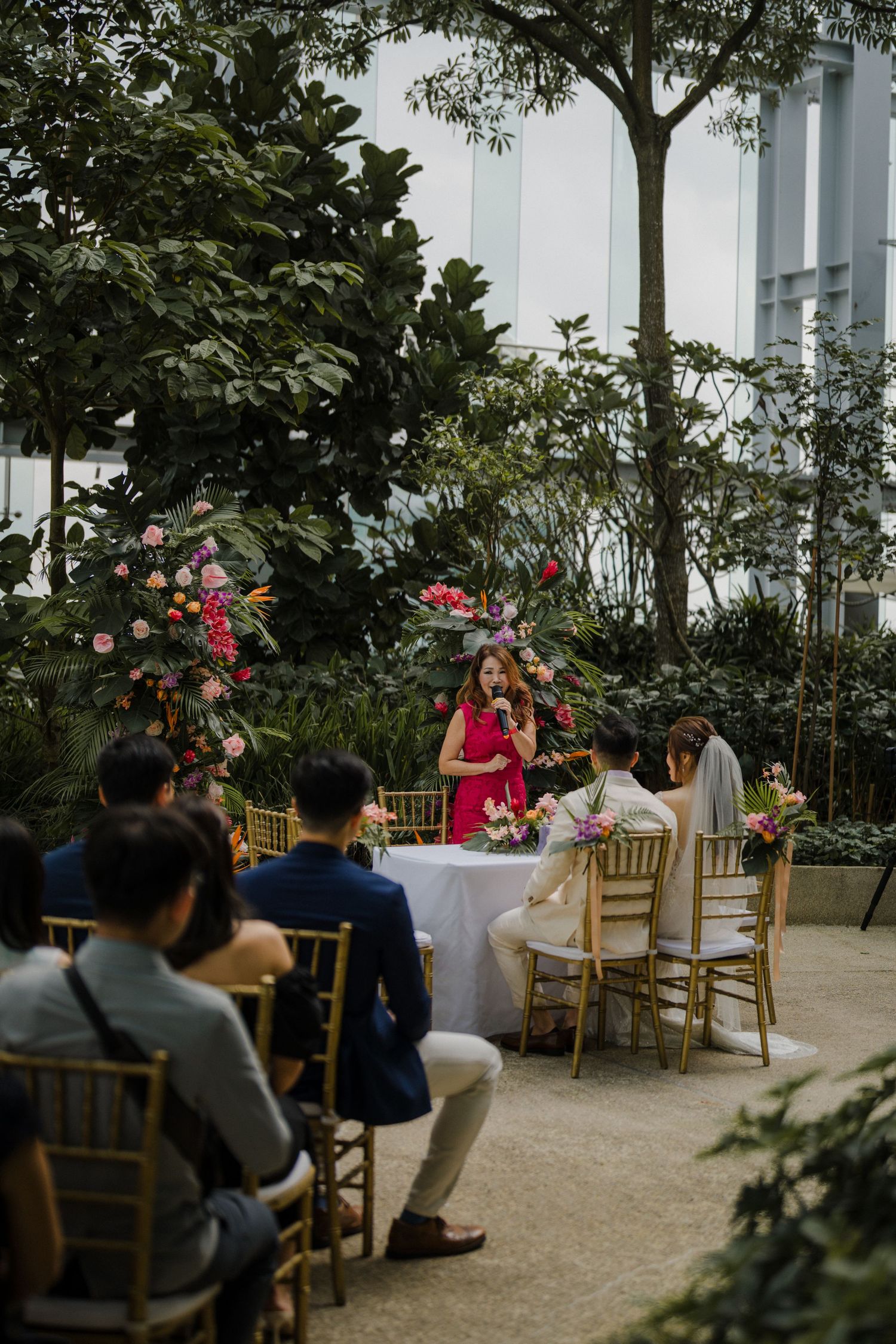 Outdoor wedding reception setup with wooden chairs and tropical garden surroundings.