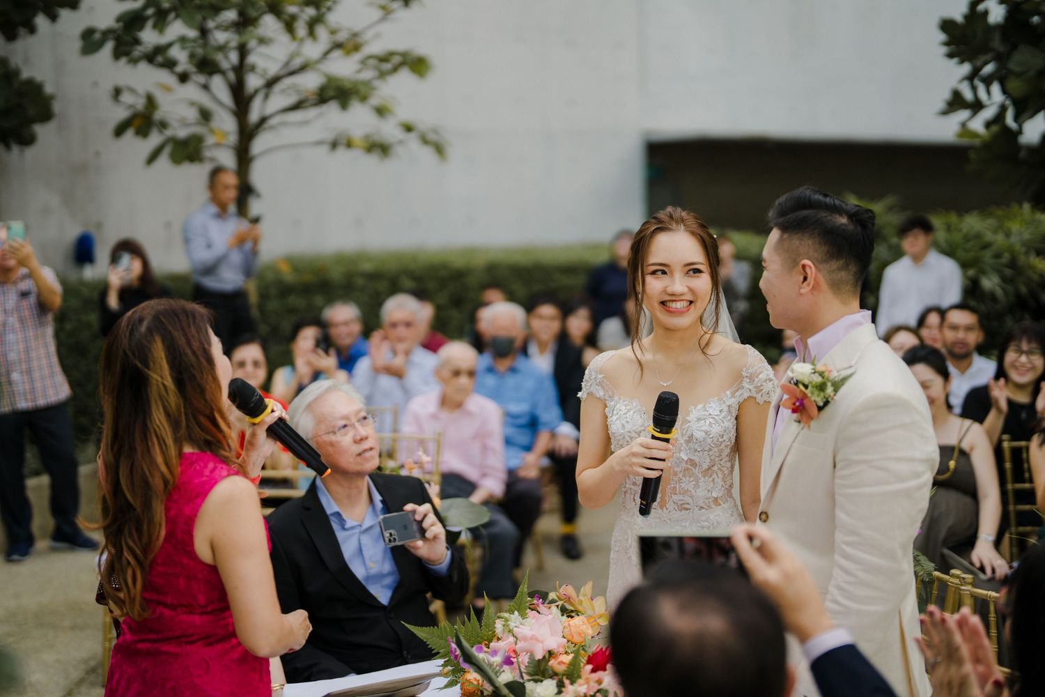 Wedding guests celebrate during an outdoor ceremony with modern building backdrop.