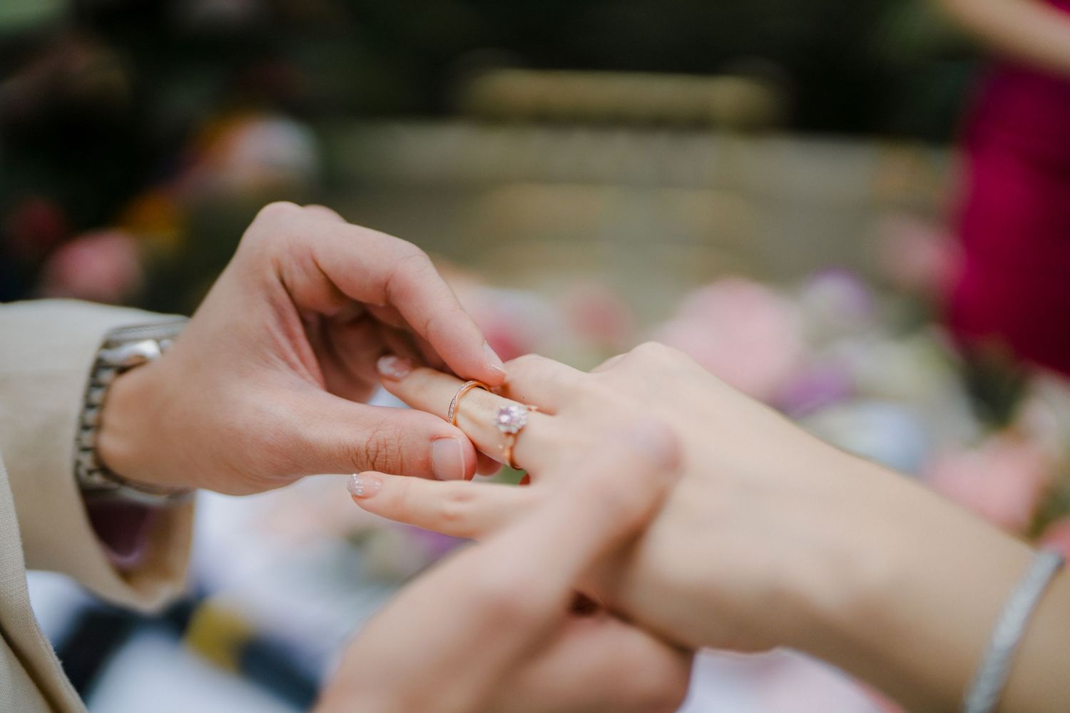 Intimate moment of ring exchange during outdoor wedding ceremony.