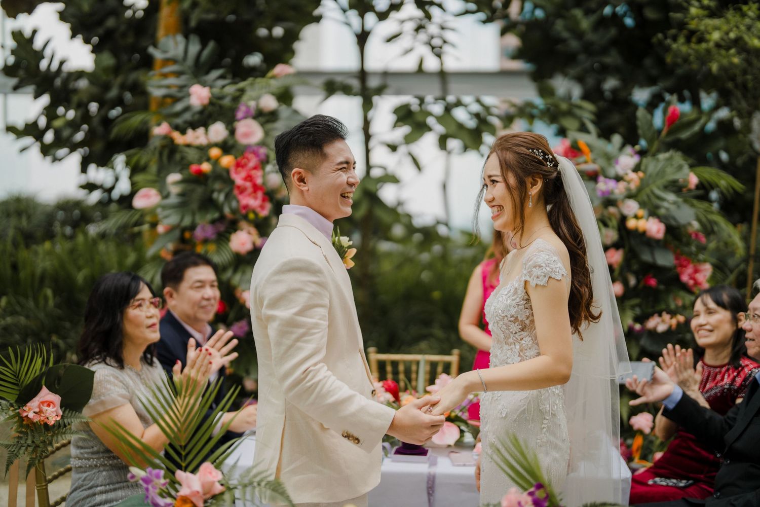 Romantic garden wedding ceremony with tropical flowers and gold chairs.