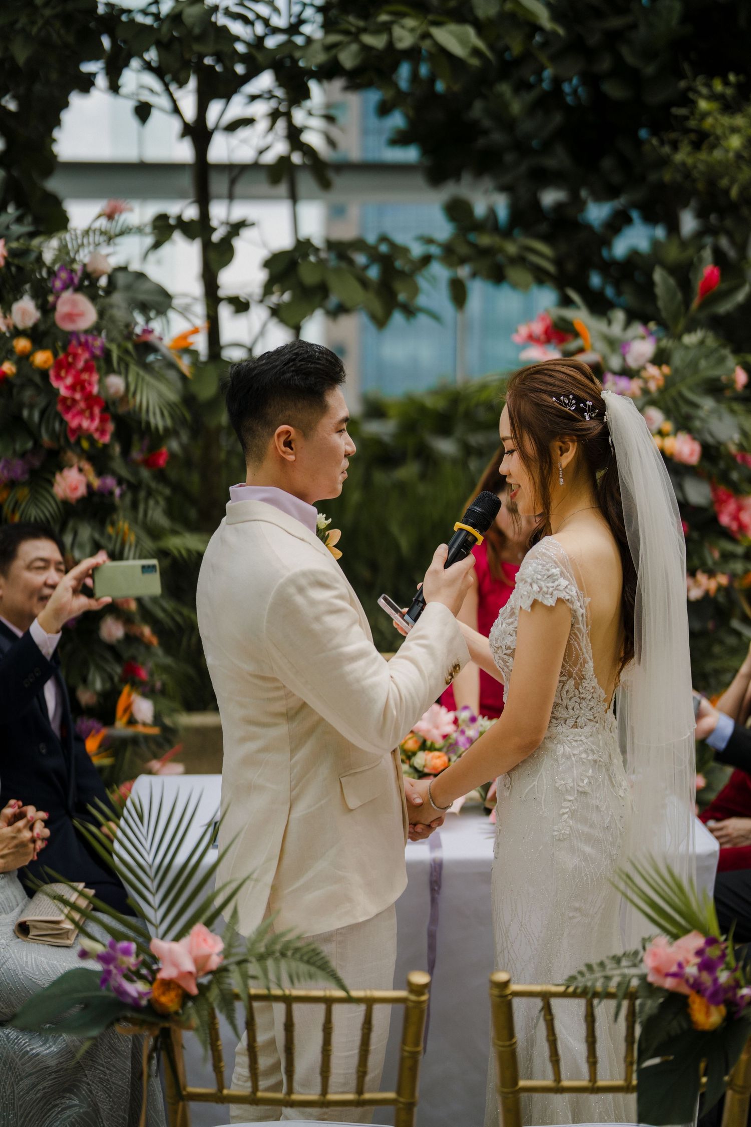 Couple shares emotional moment during outdoor wedding ceremony surrounded by flowers.