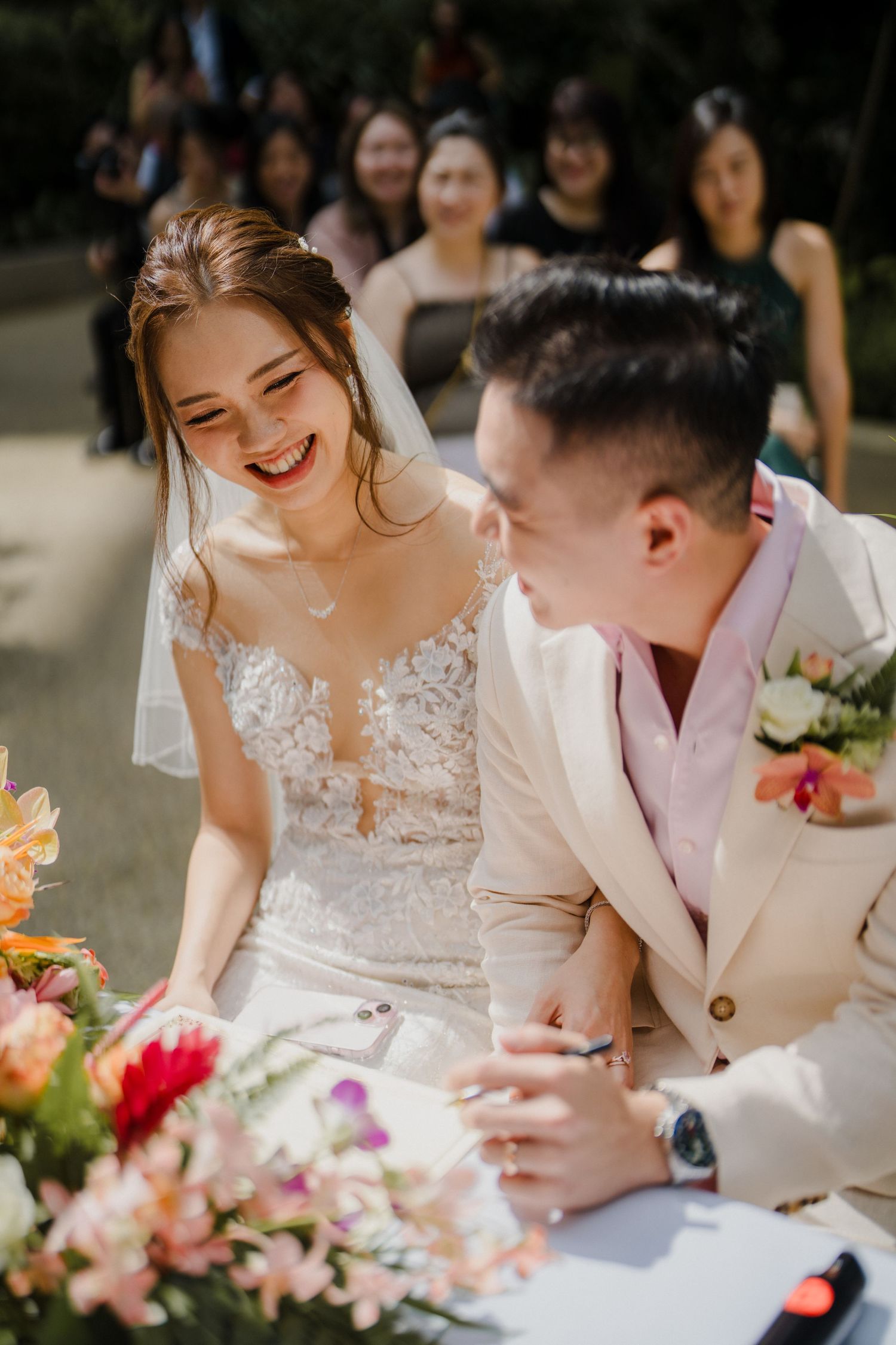 Bride and groom sharing a joyful moment while signing marriage paperwork.