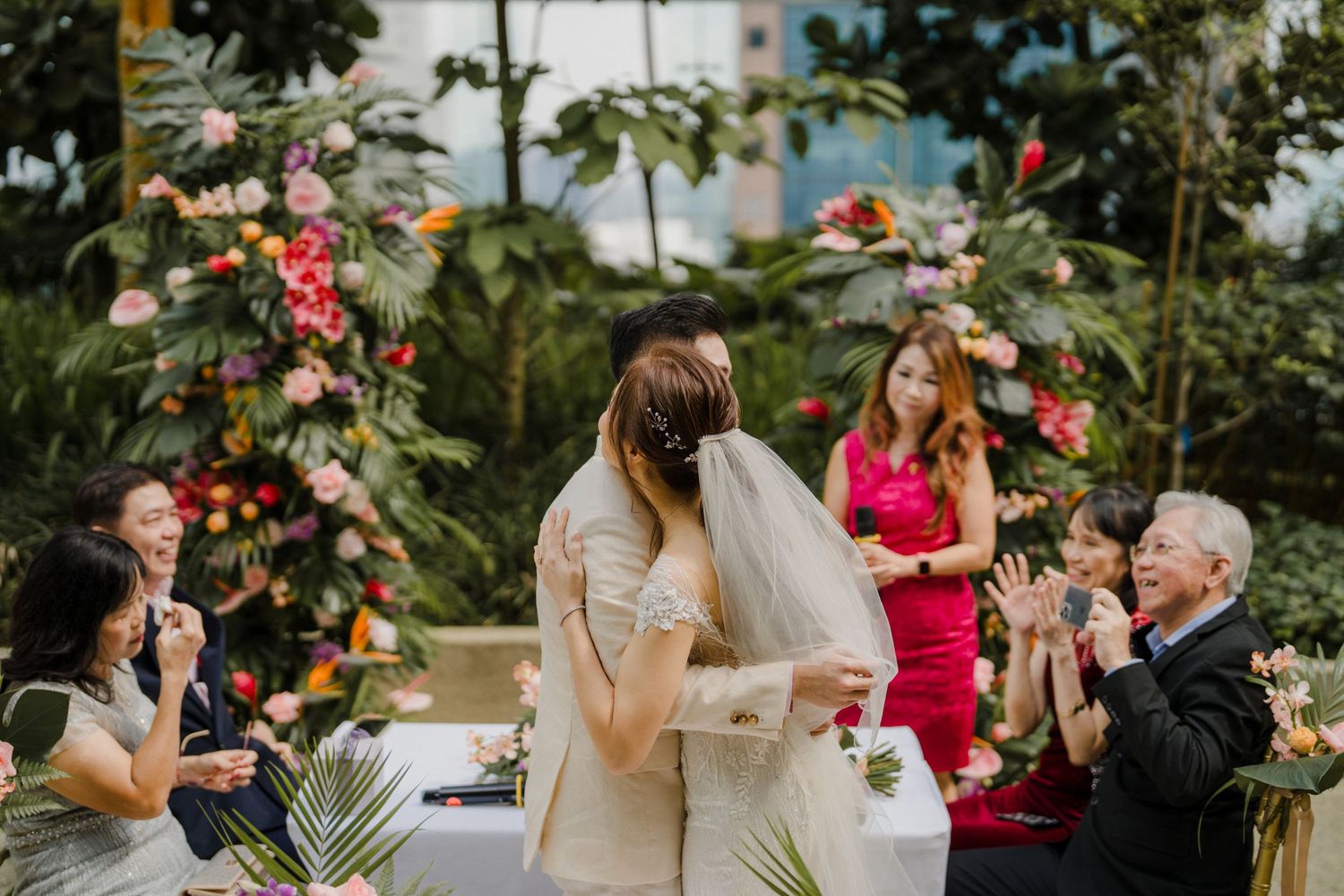 Outdoor wedding celebration with guests and tropical flower arrangements.