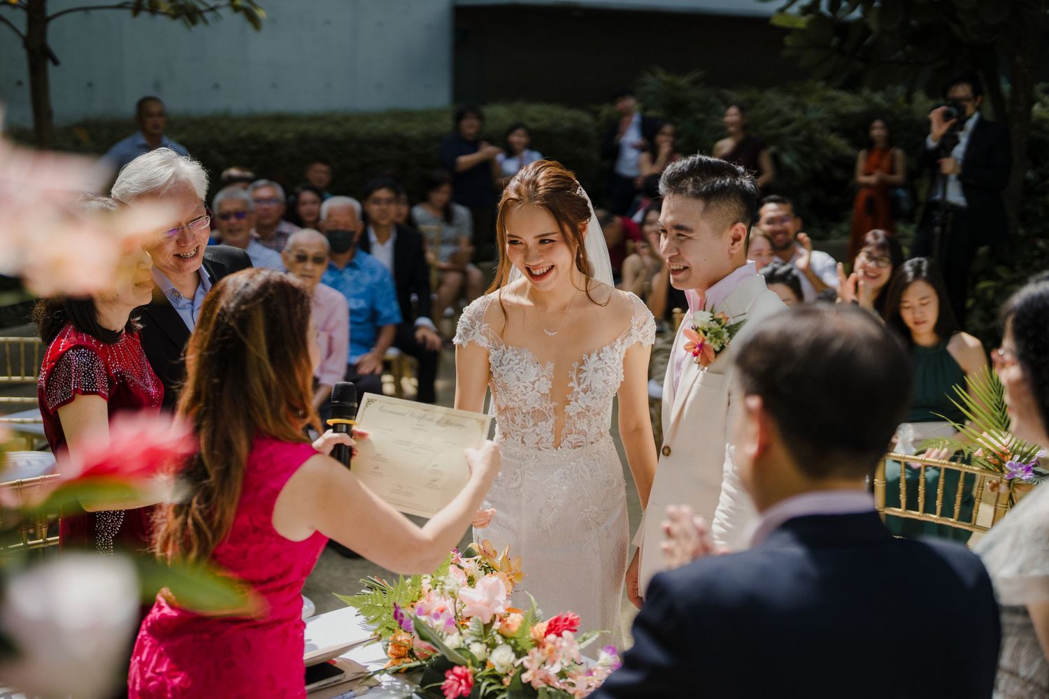 Garden wedding ceremony with guests and pink floral arrangements.