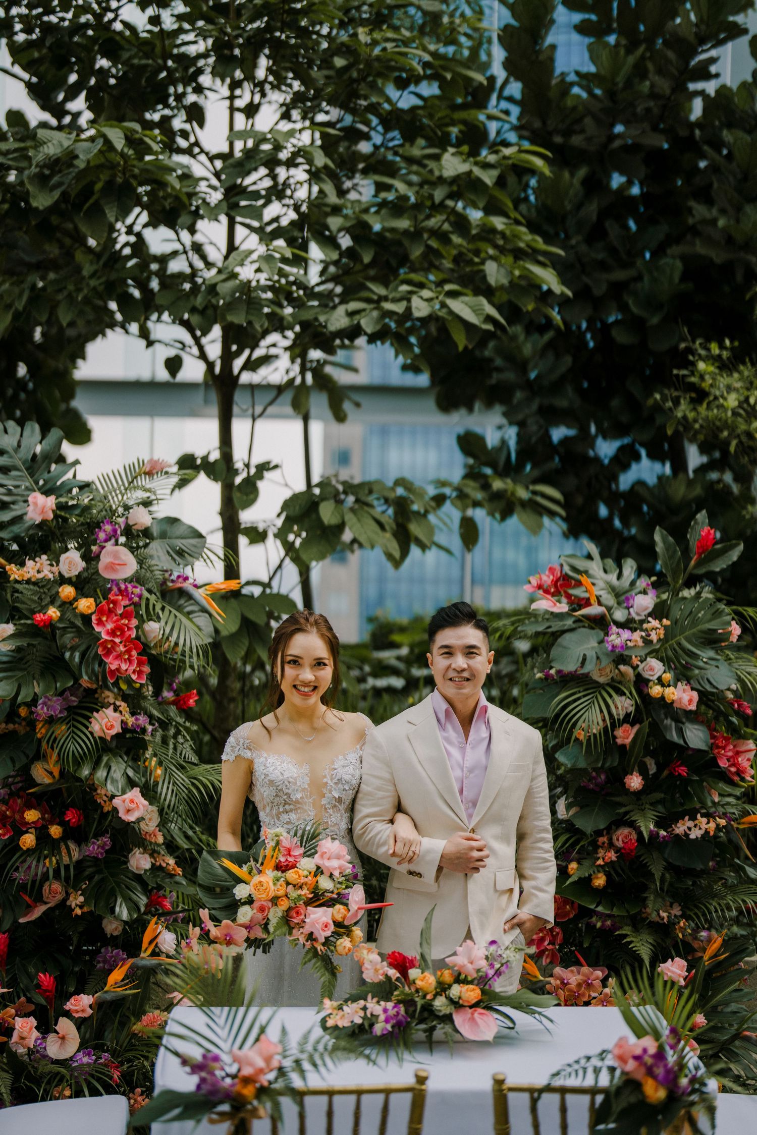 A garden wedding scene with tropical flowers and modern architecture in the background.