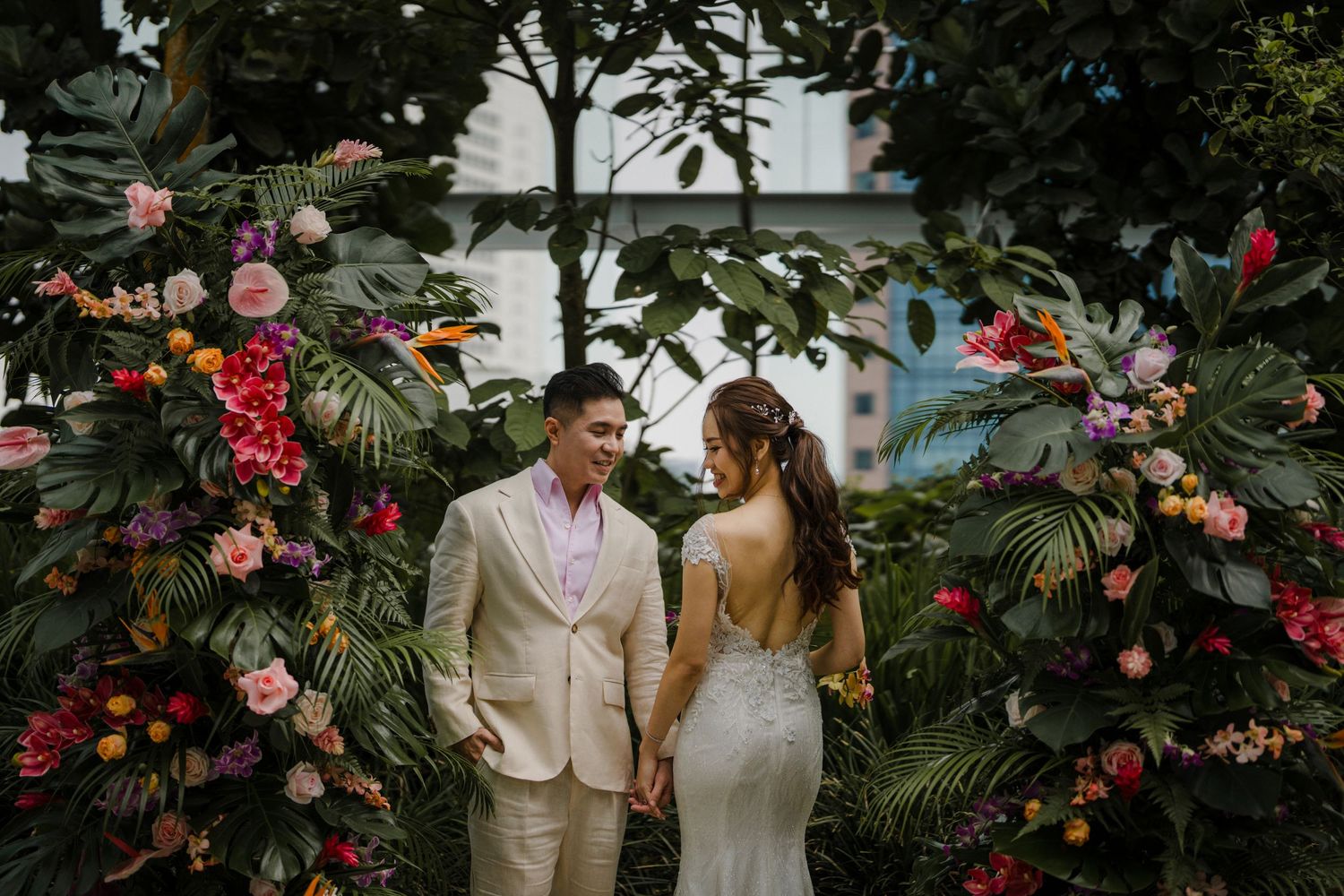 A couple shares a moment among lush foliage and colorful tropical blooms.