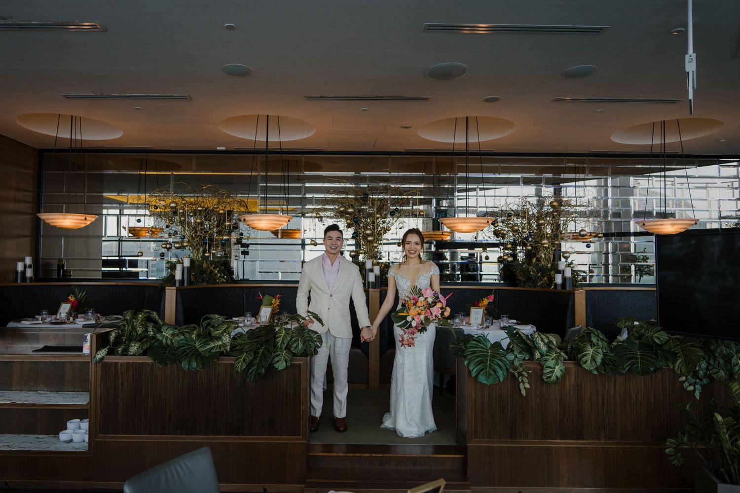 An indoor wedding venue with modern lighting and botanical decor.