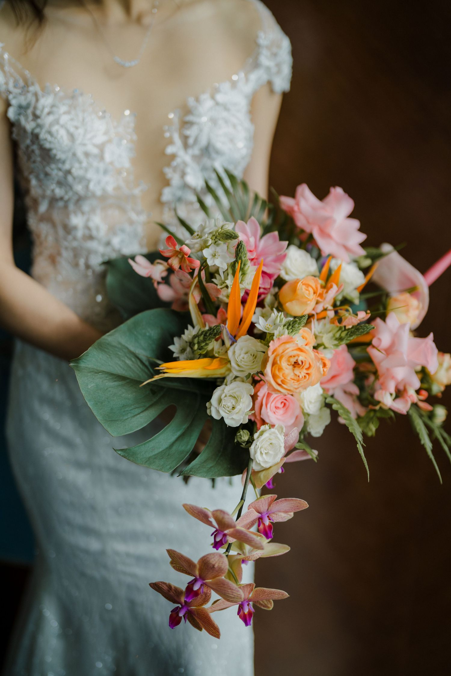Close-up of a vibrant tropical wedding bouquet with orange, pink and purple flowers.