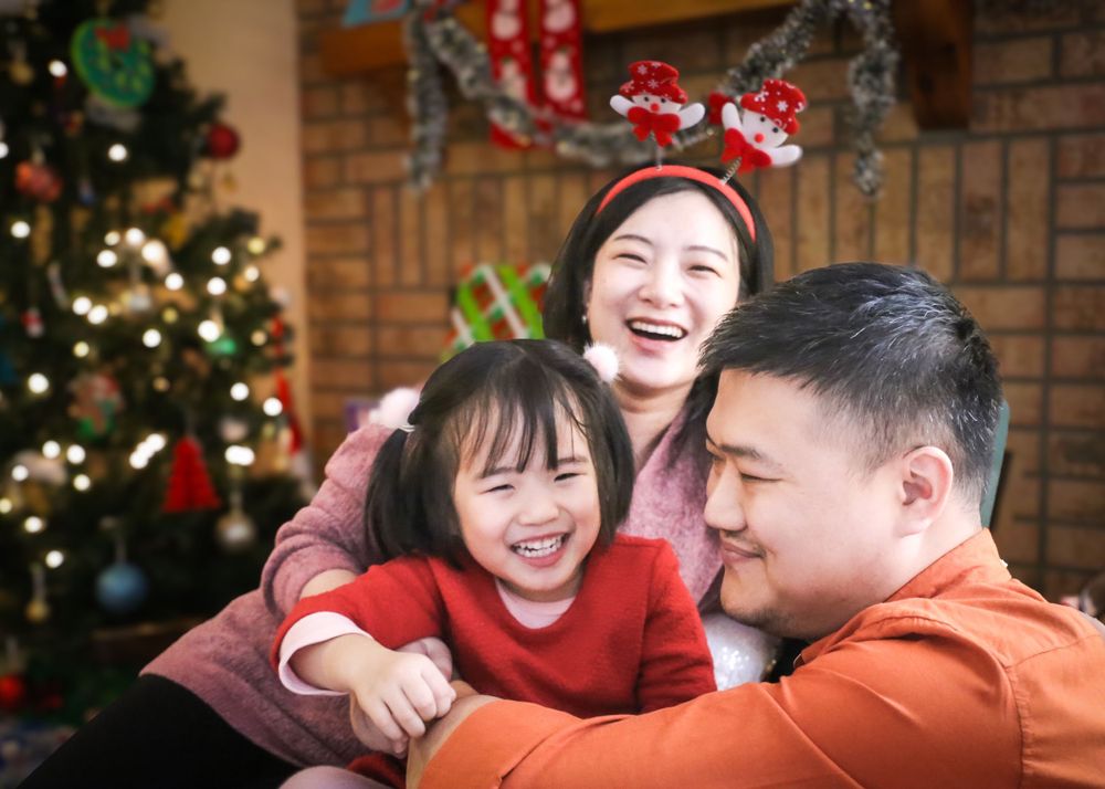 Family sharing joyful moment in front of Christmas tree with holiday decorations.