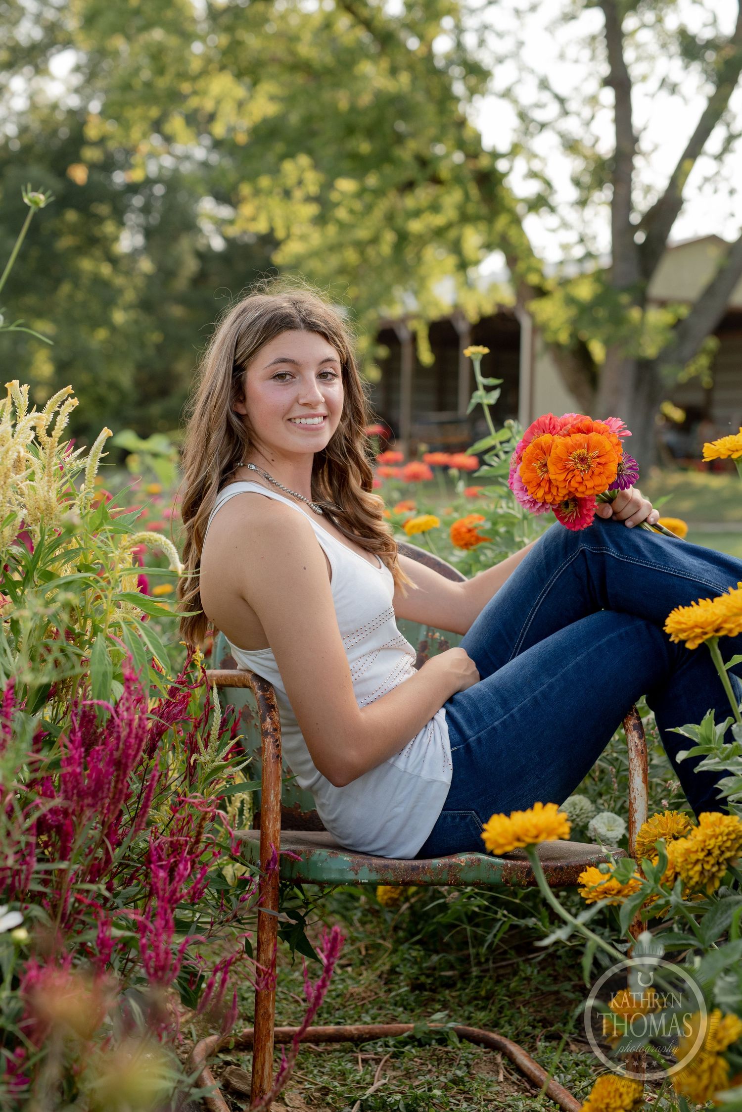 Person sitting in rustic chair among bright summer flowers and celosia plants.