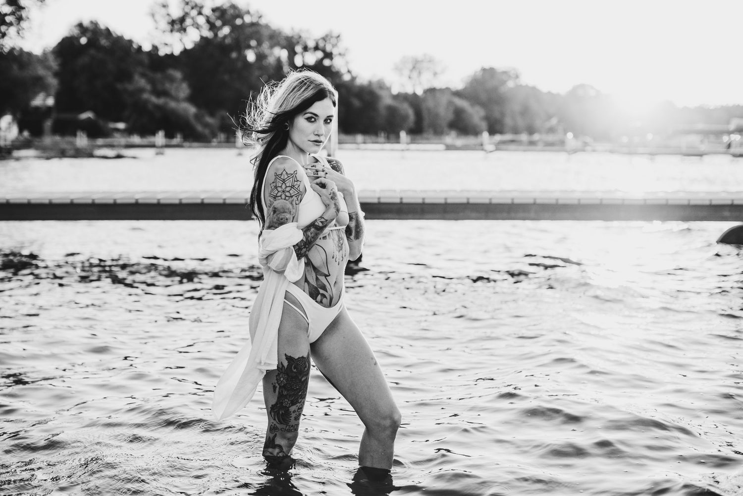 Woman standing in water wearing boots during golden hour photography session.