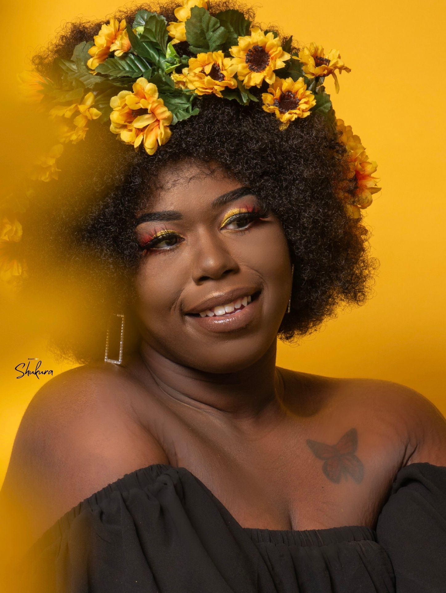 Sunflower-adorned portrait against golden background with natural lighting.