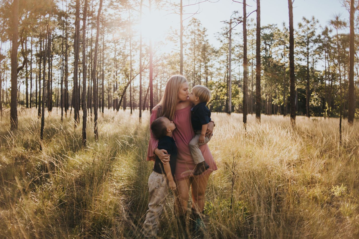 Couple sharing playful moment in sun-drenched forest clearing during golden hour.