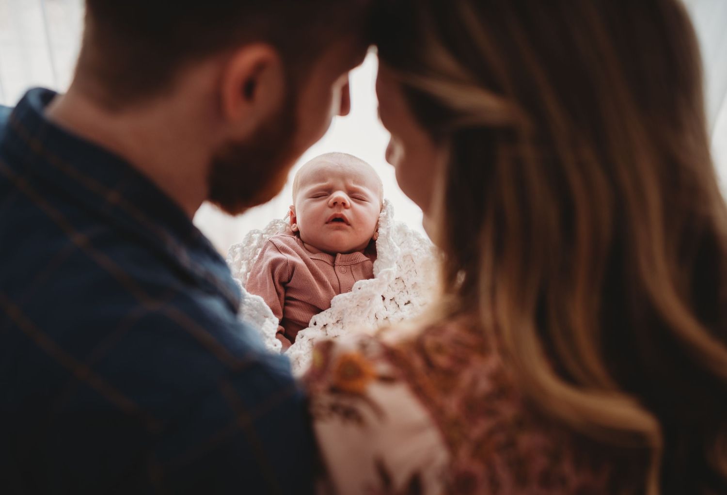 Intimate indoor family photoshoot with baby and black dog on living room carpet.