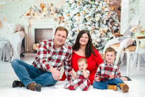 Family Christmas portrait with matching plaid outfits and holiday decorations.