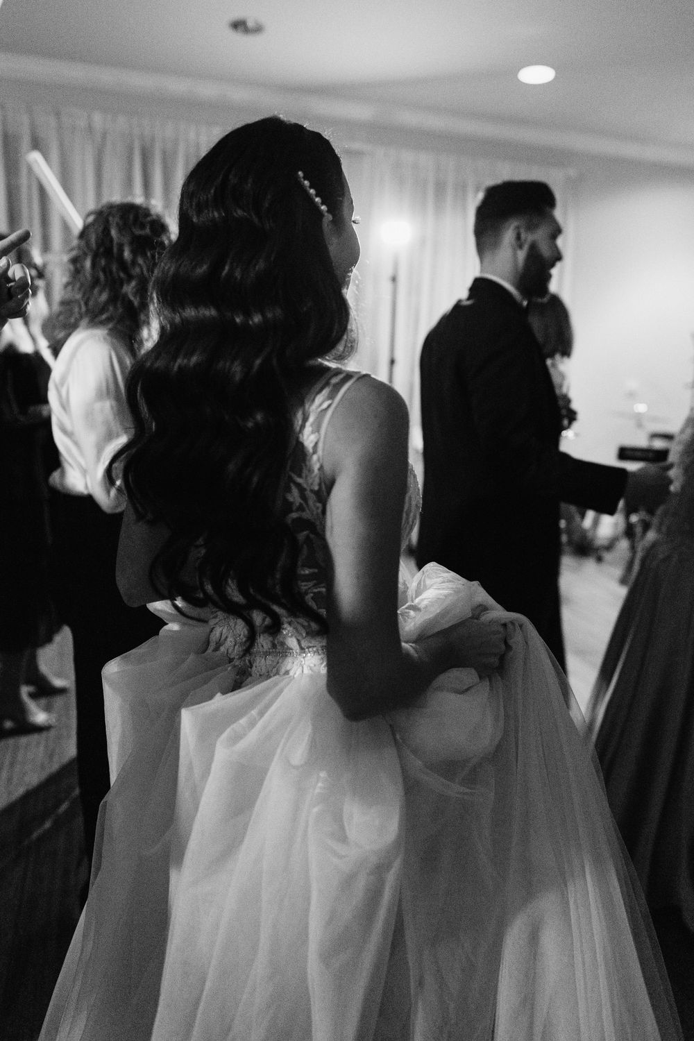 Wedding party in formal attire stands together during reception in elegant ballroom.