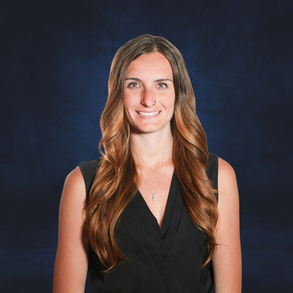 Professional headshot of someone in sleek black attire against a dark blue background. Quad Cities Business Headshot Photography