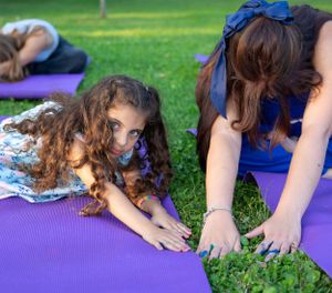 Close-up of hands stretching on purple yoga mats during outdoor exercise session.