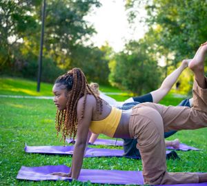 Person demonstrating yoga poses on a purple exercise mat in a sunny park.