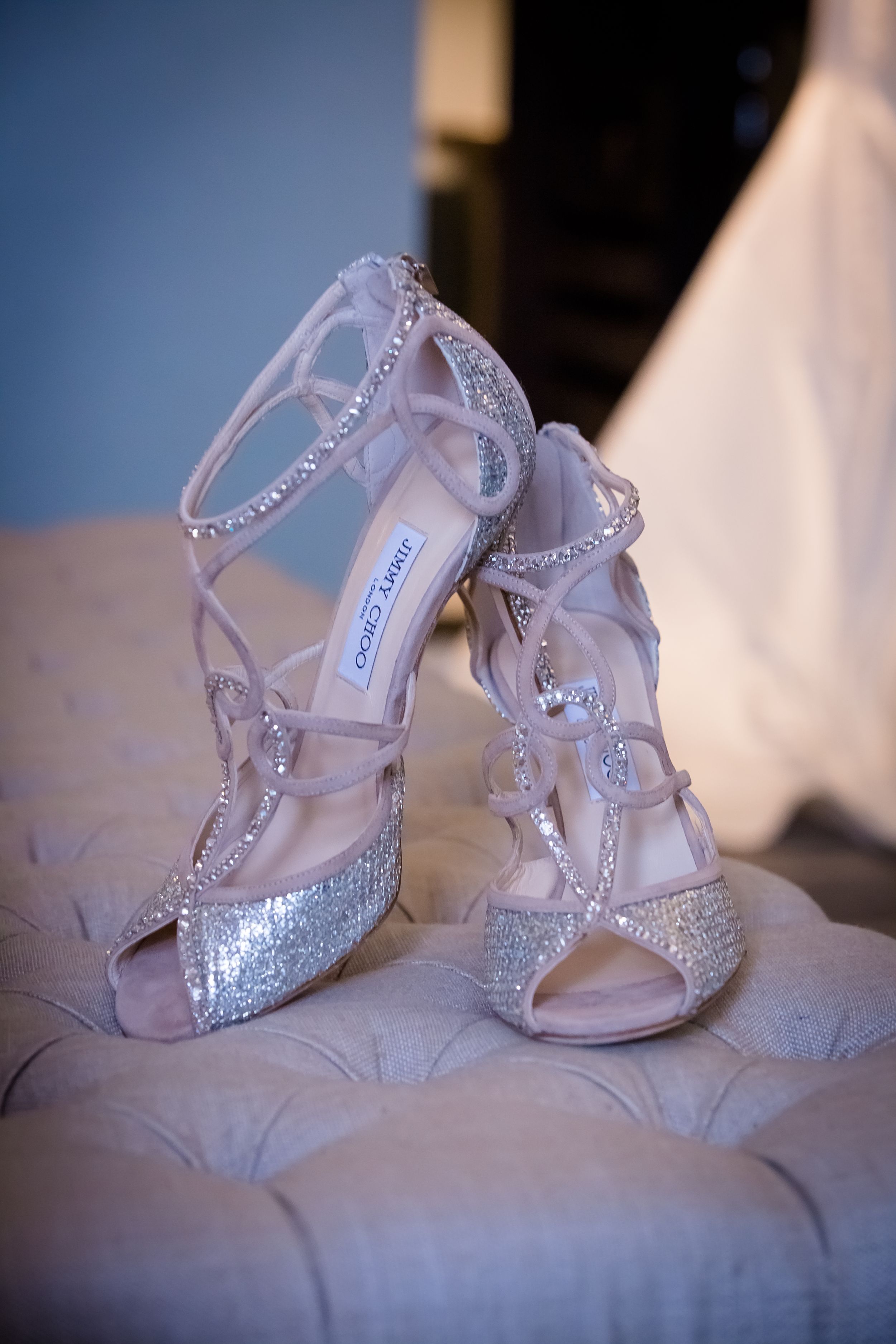 Sparkling crystal-encrusted bridal shoes displayed on textured fabric.