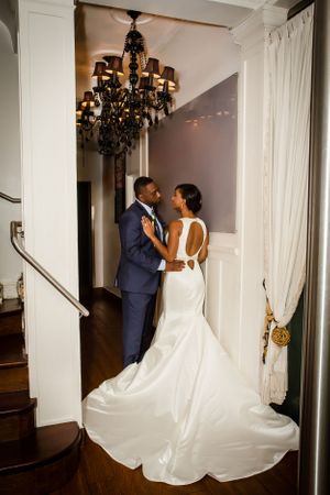 Wedding couple shares intimate moment in elegant white interior setting.