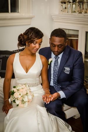 Intimate wedding portrait showing tender moments between couple seated on elegant furniture.