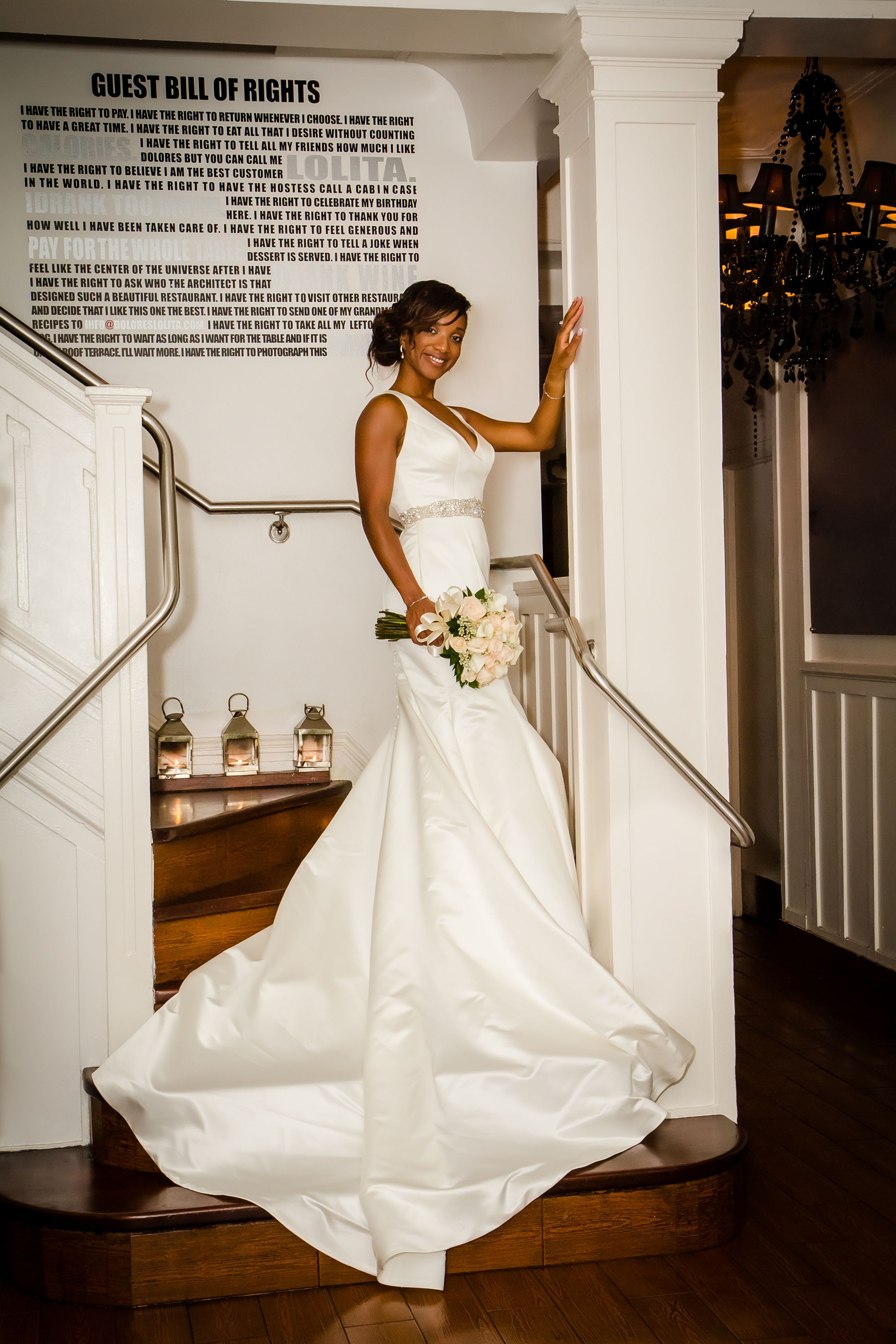 Bride in flowing white dress poses dramatically against wall with text display.