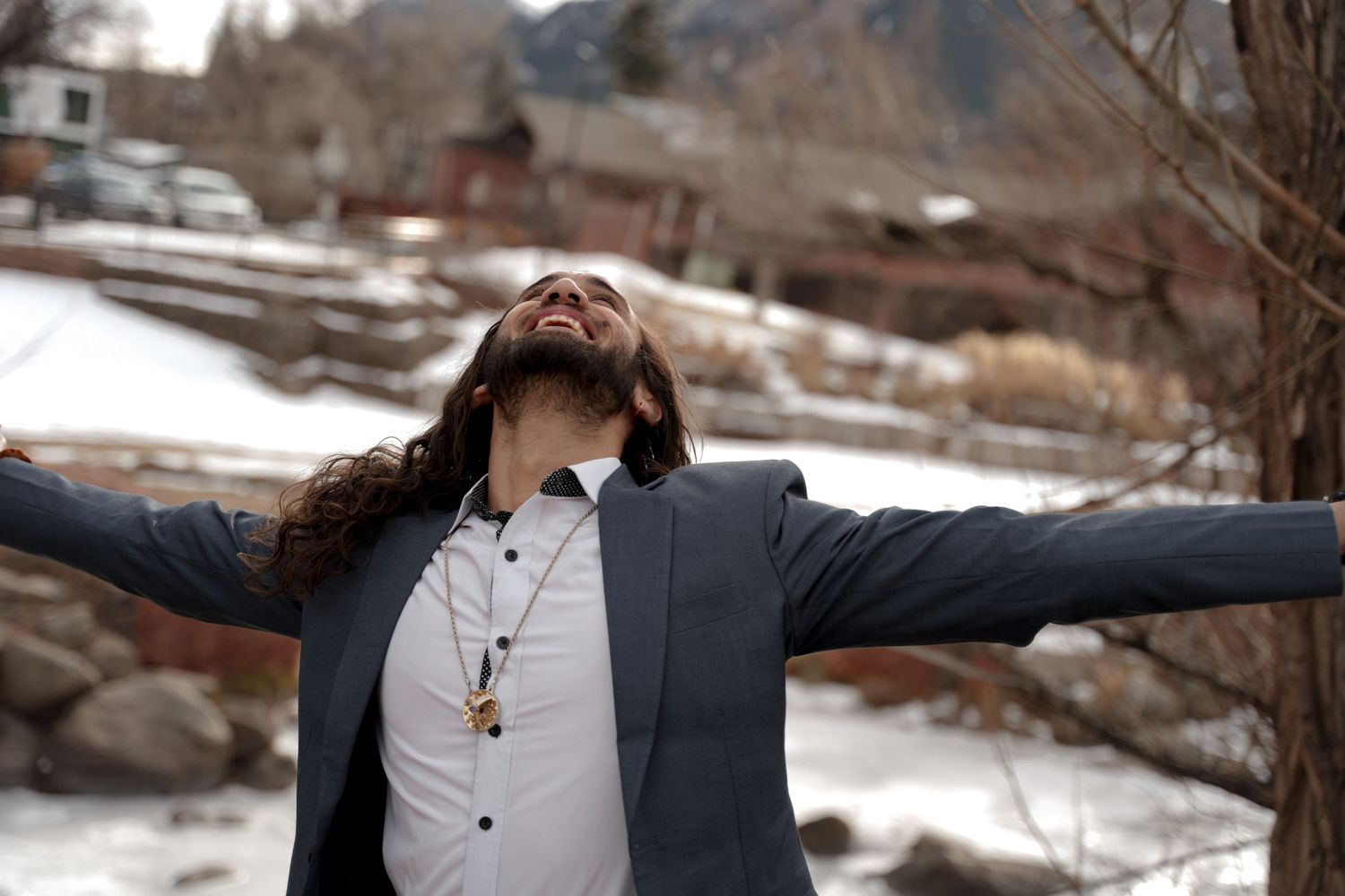 Winter scene with person stretching arms wide against snowy mountain backdrop.