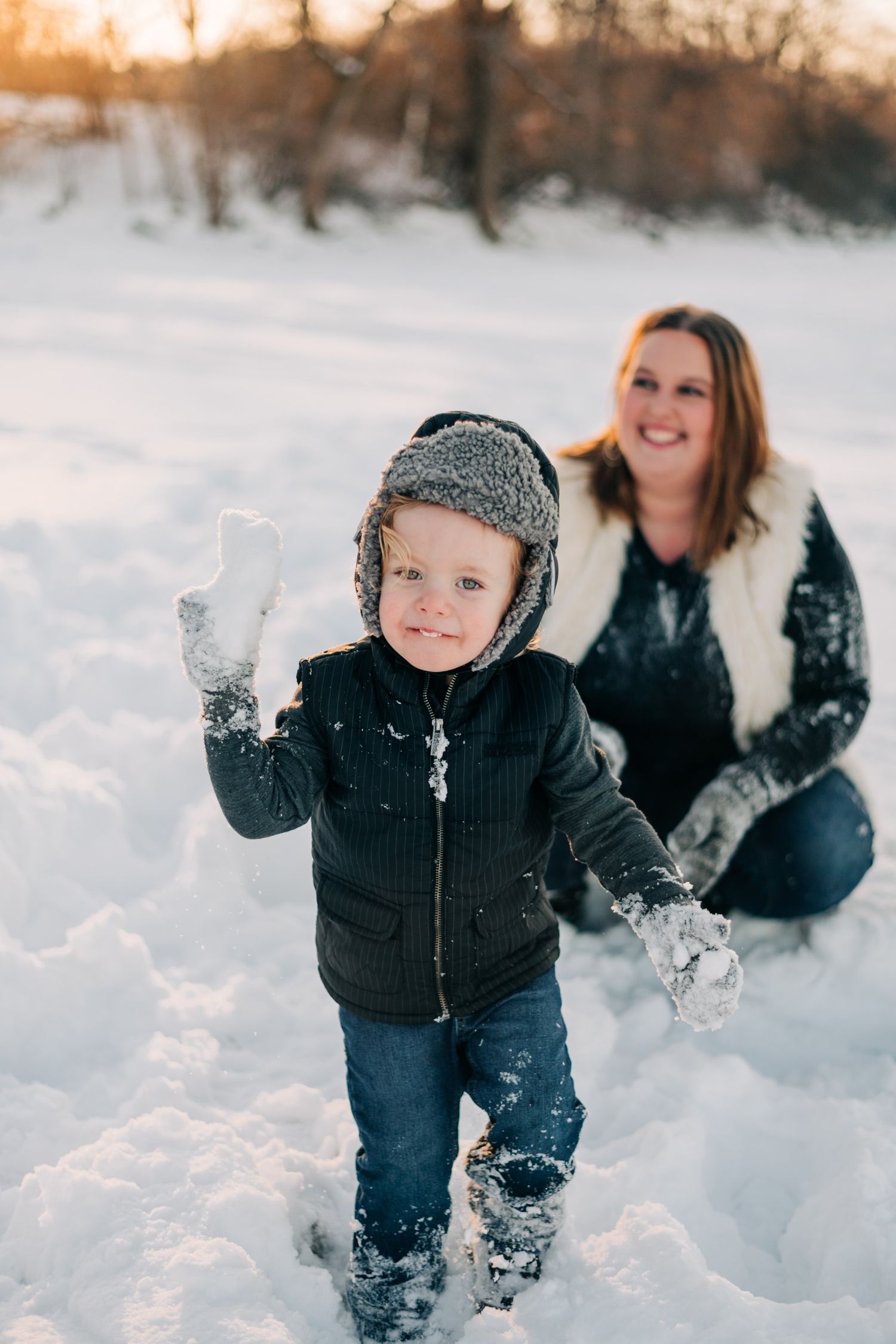 photo of a little boy about to throw a snowball on a snowy beach at sunset