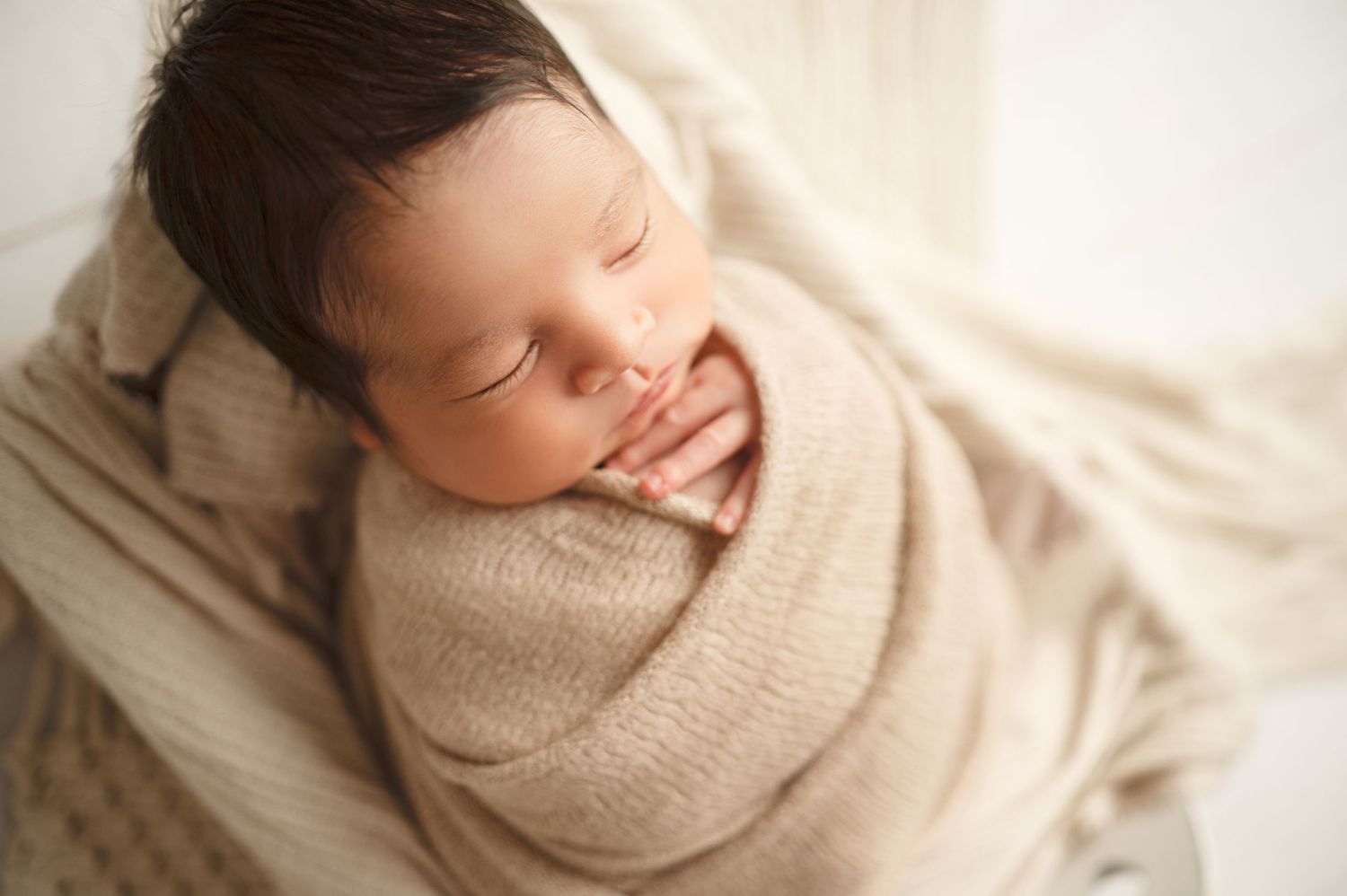 Professional newborn photography series featuring baby swaddled in cream-colored wrap.