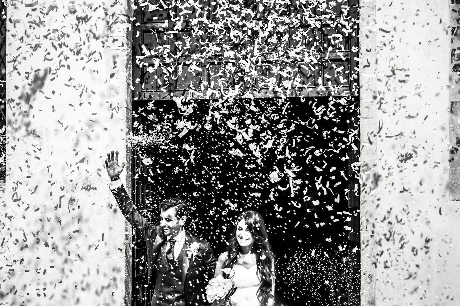 marito e moglie escono delici dalla chiesa dopo il matrimonio accolti dal lancio del riso
