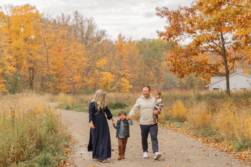 family with two little boys walking in a park in October in Oakland County Michigan