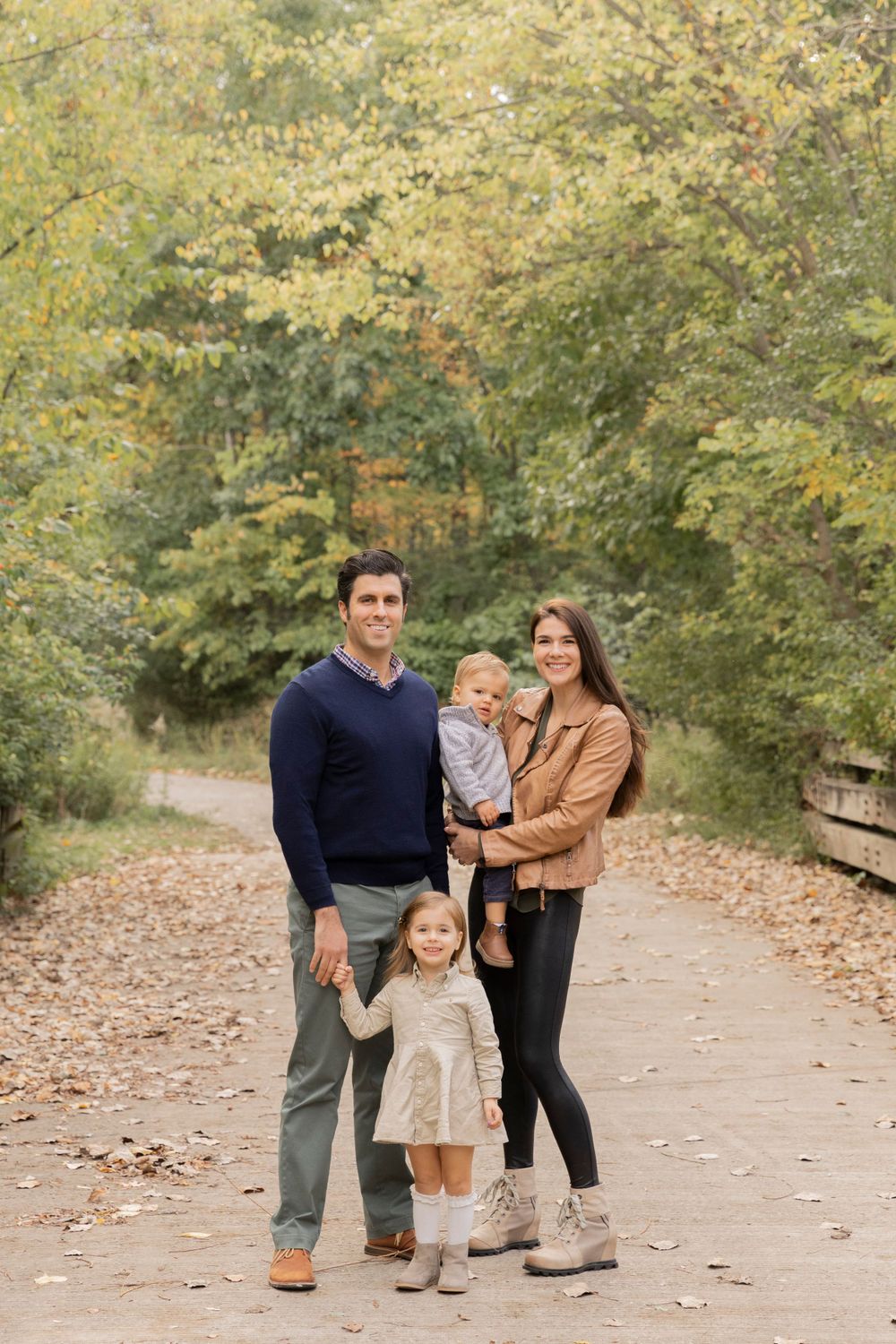 family of four standing on a bridge at a park entrance in Oakland County Michigan in late September