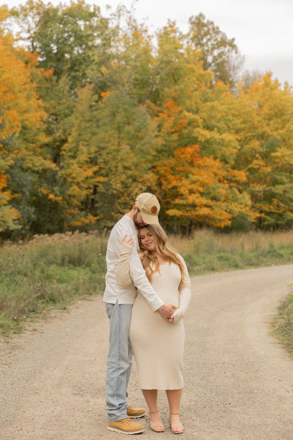 pregnant couple wearing creams and beiges cuddled up together at Douglas Evans nature preserve in october