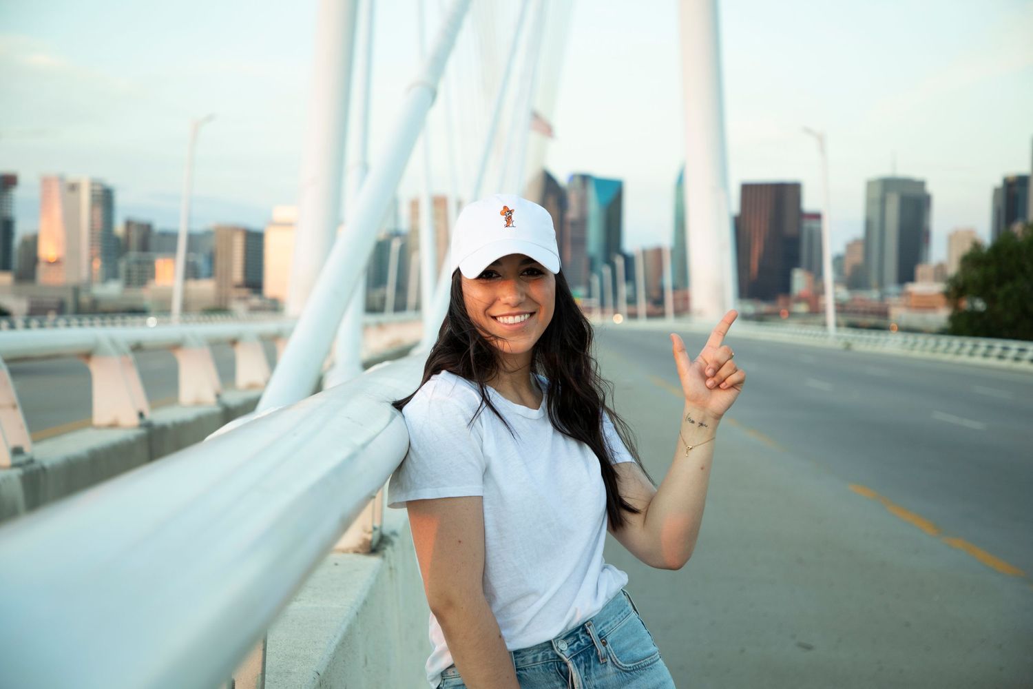 Casual portrait on a suspension bridge with downtown skyline in background.
