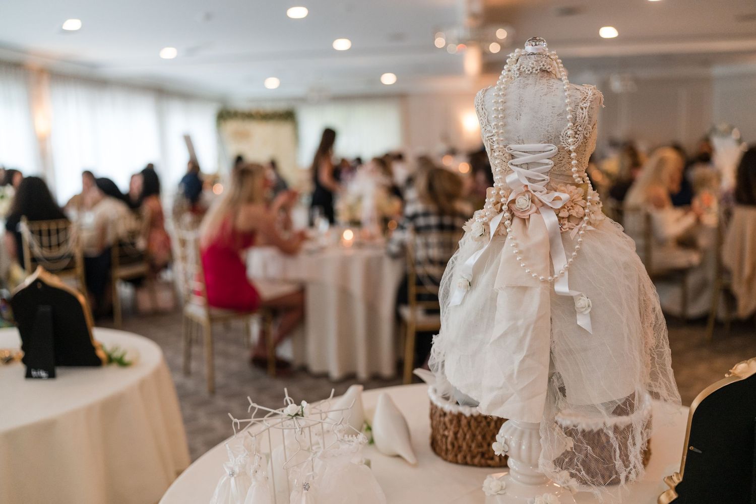 Decorative wedding dress display at elegant reception with white table settings.