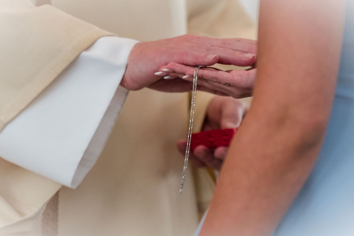 Close-up of hands during religious ceremony with priest performing blessing.