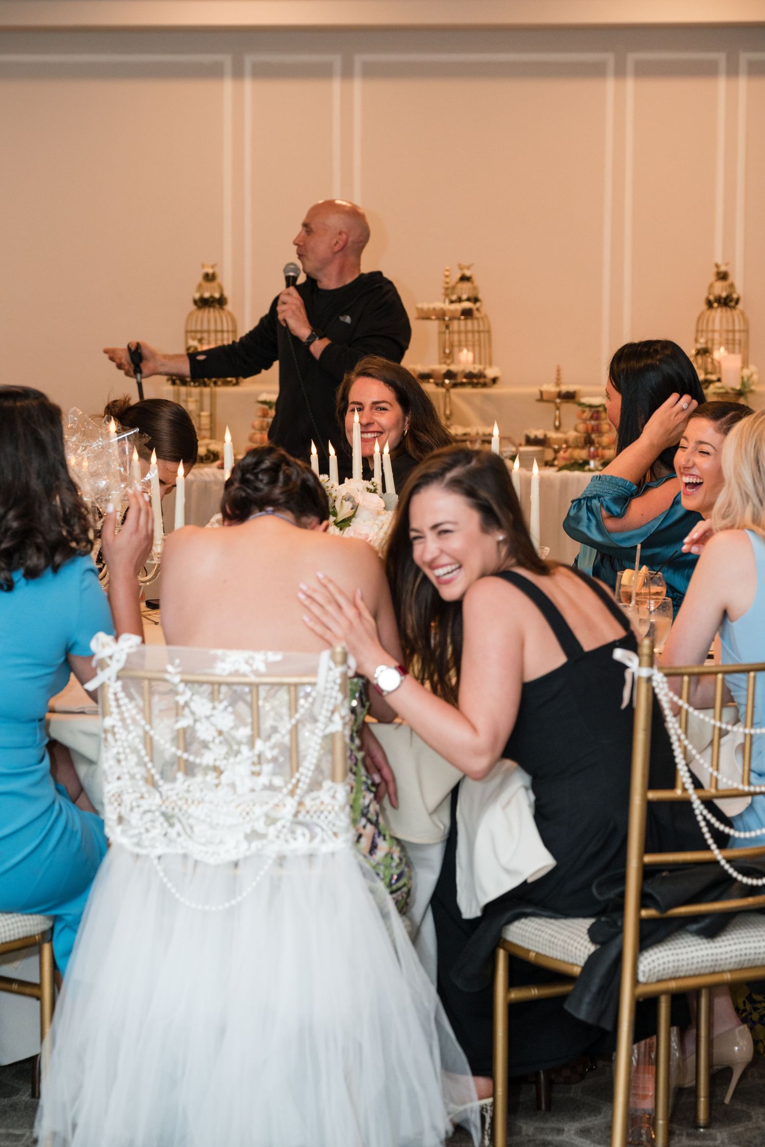 Wedding reception scene with guests laughing and celebrating at decorated table.