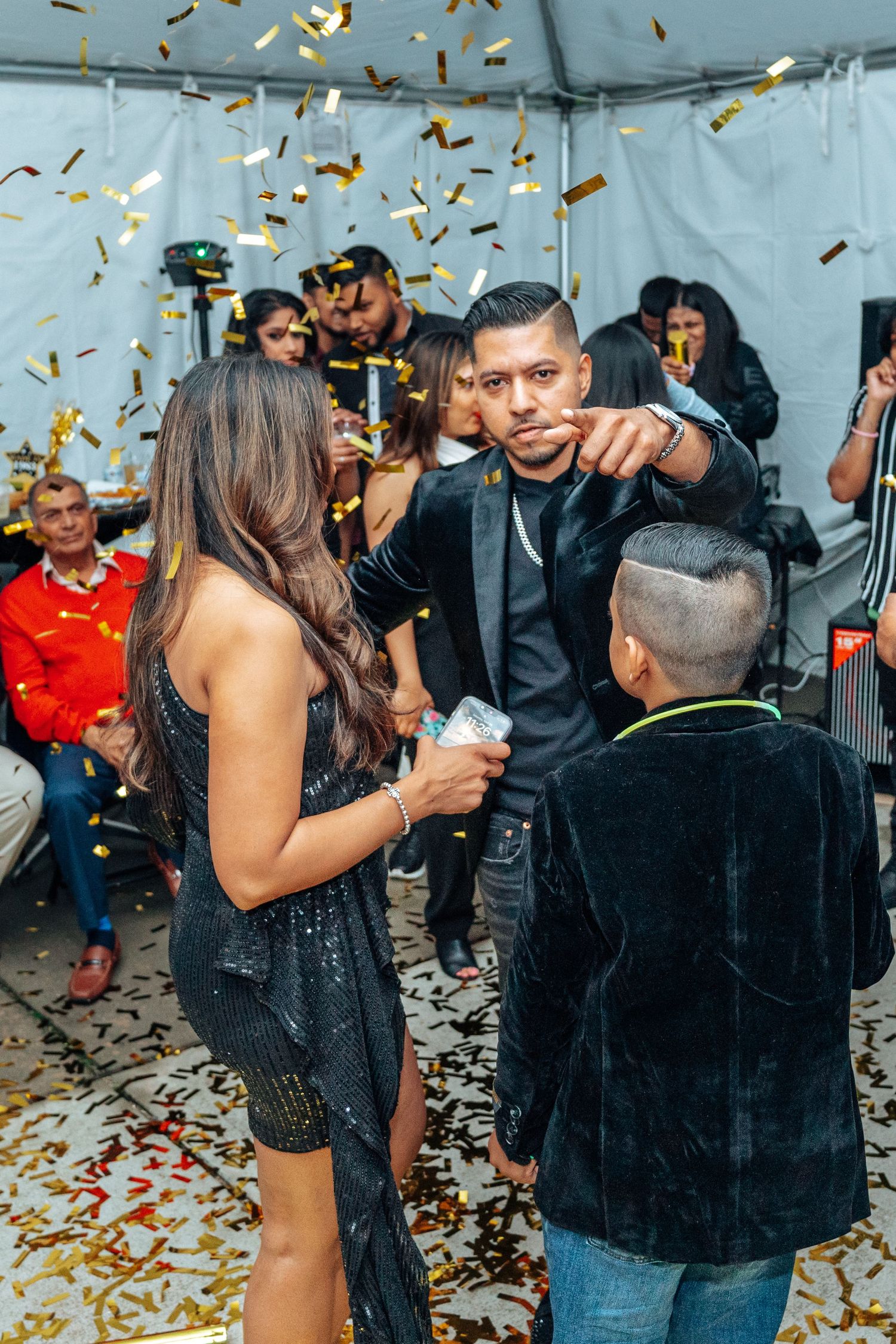 Party celebration with gold confetti falling and guests in formal attire.