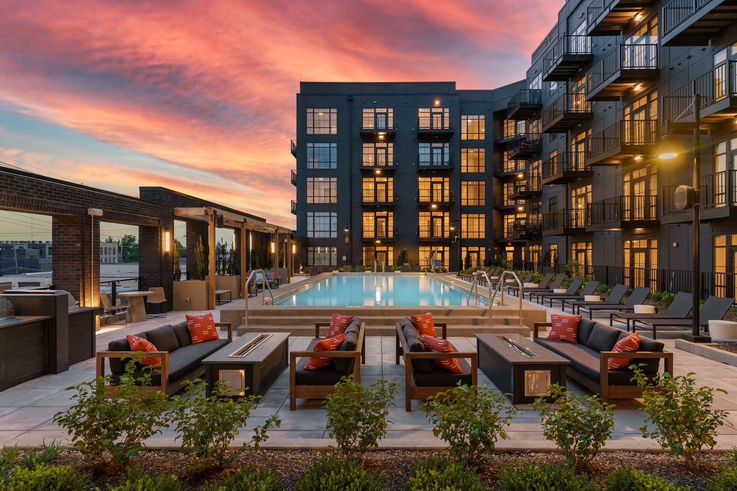 Pool and apartment amenities at twilight with a spectacular sunset showcasing new residential commercial architecture.